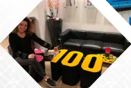 Logohocker Tisch in Form einer 100 steht vor einem Sofa