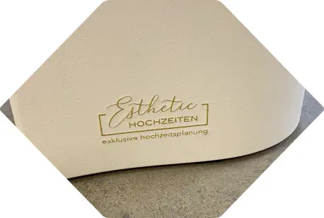 goldene Bestickung eines Logos auf einem weißen Sitzhocker