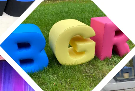 bunte Sitzbuchstaben Hocker BGR stehen aufrecht in Wiese