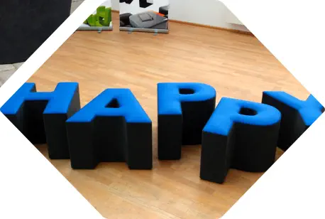 Buchstaben HAPPY als Sitzelemente in blau-schwarzer Teillederausführung im Raum