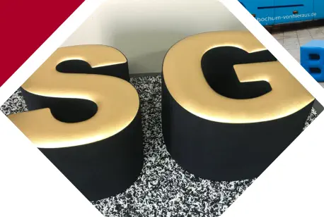 goldene Buchstaben SG als Sitzhocker stehen in einem Raum