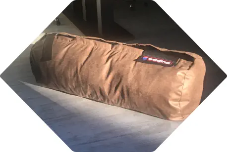 eine übergroße Federmappe als brauner Sitzsack liegt auf dem Boden