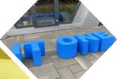 Buchstaben IT One stehen als Hocker vor einem Büro