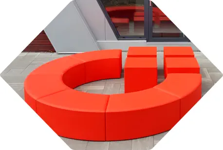 rotes BVMW Logo steht als Sitzhocker im Freien vor einem Büro