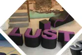 Buchstaben LUST, ein Würfel und eine Relaxliege stehen im Keller 
