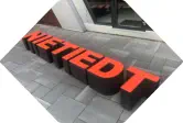 Buchstaben Nietiedt als Hocker stehen vor einem Büro