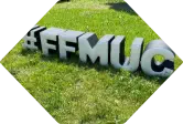 #FFMUC steht aufrecht als Sitzhocker in Wiese