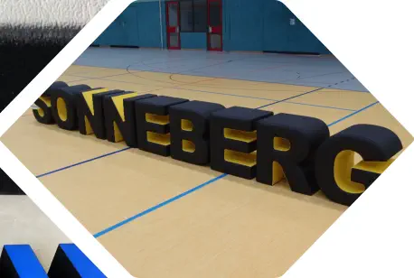 Sitzbuchstaben SONNEBERG in schwarz-gelben Leder stehen aufrecht in Turnhalle