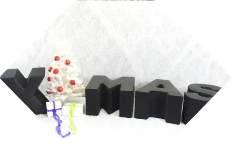 Sitzbuchstaben mit Winterdeko bilden das Wort X-Mas als Weihnachtsgruß