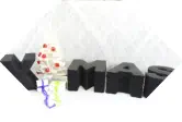 Buchstaben XMAS stehen als Deko vor Weihnachtsbaum